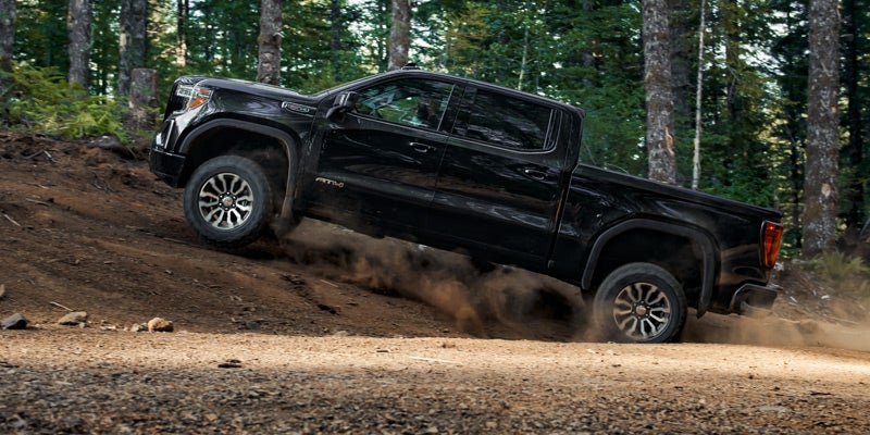 black GMC Sierra 1500 climb in forest road