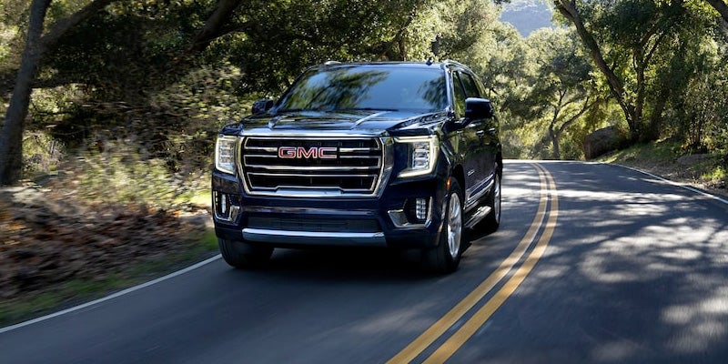 black GMC Yukon XL in forest road