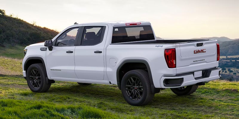 Side angled Rear view of a white GMC Sierra 1500 parked on grass