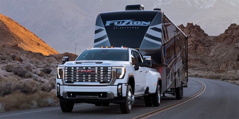 white GMC Sierra 2500 towing large camper uphill